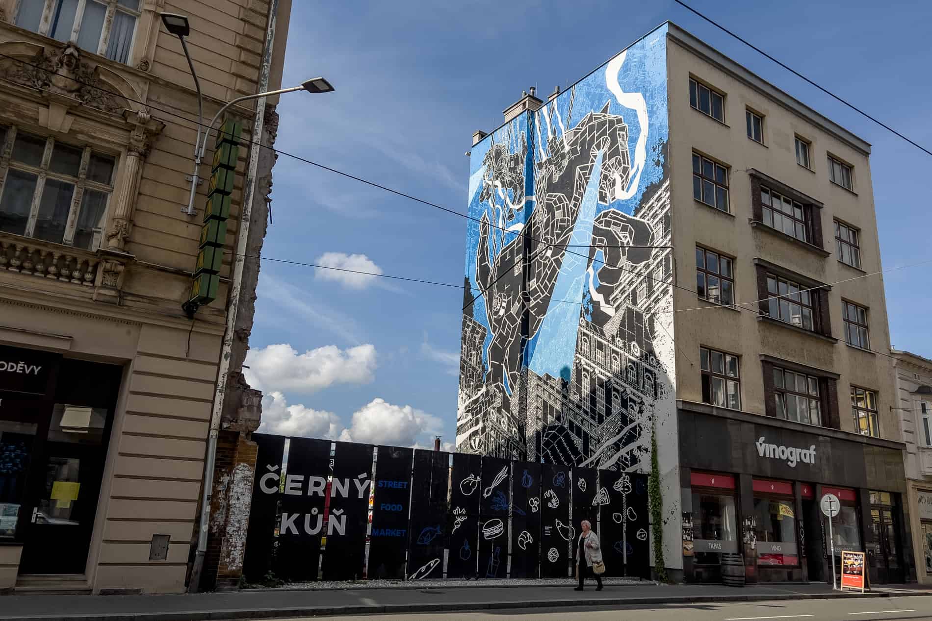 Street art mural in Ostrava of a black horse galloping over the city.