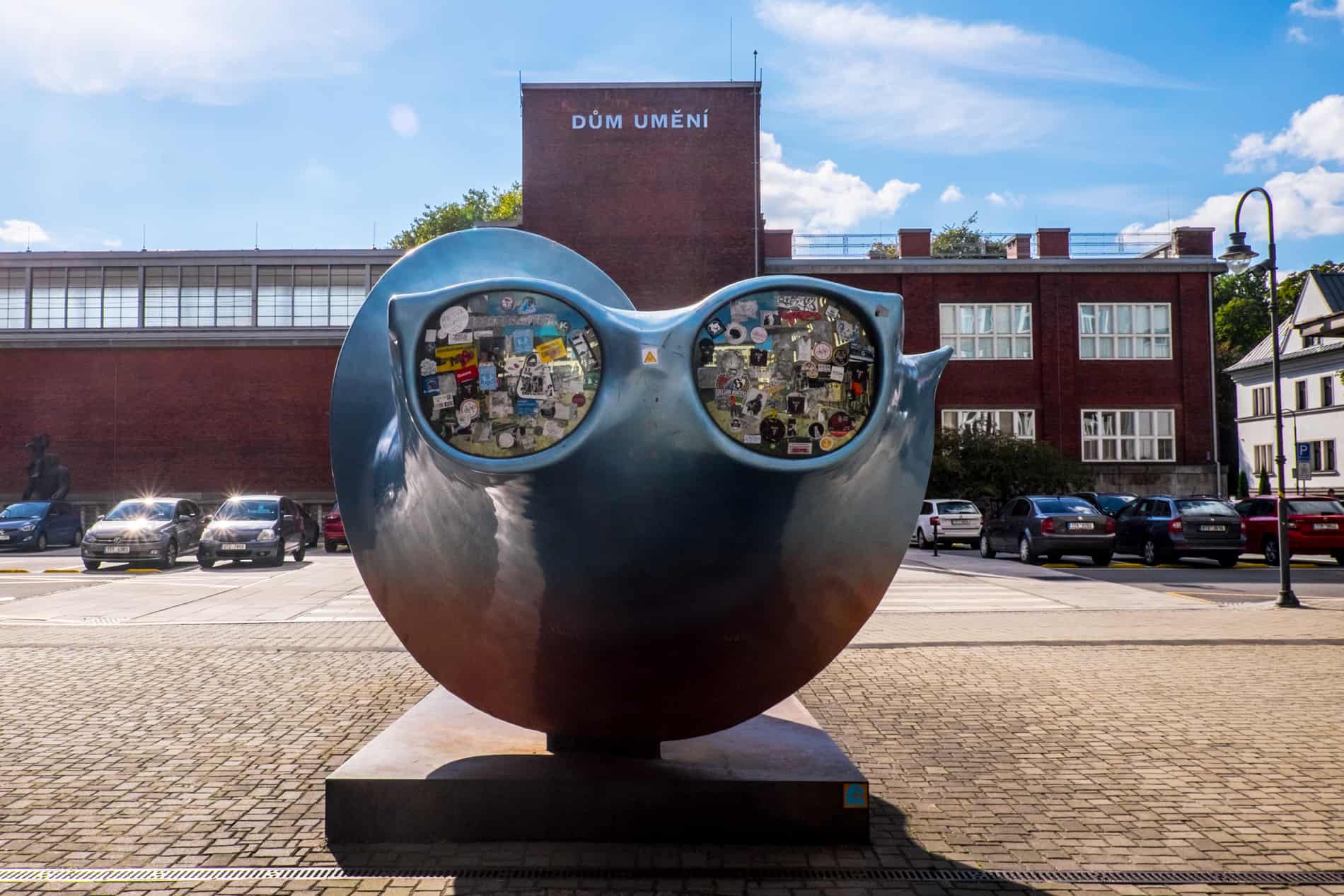 A blue sculpture with sticker covered sunglasses outside the Ostrava Gallery of Fine Arts.