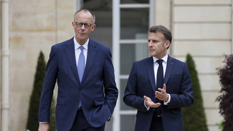 German Chancellor Friedrich Merz, left, walks with French President Emmanuel Macron.