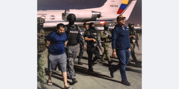 Ecuadorian police escort drug lord Fito during extradition to the United States after his prison escape, night operation near military jet"