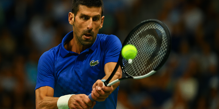 Novak Djokovic Becomes Oldest to Reach All Grand Slam QFs 1 Novak Djokovic in action during a Grand Slam match, hitting a forehand shot with focus and intensity, crowd visible in the background.